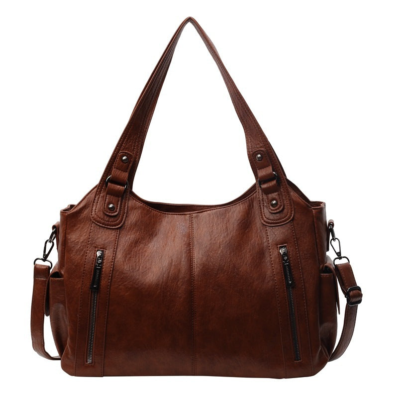 Kaldar stijlvolle leren tas in Koffie, met een elegant design en dubbele handvatten. De tas heeft voorvakken met ritssluitingen en een afneembare schouderriem, wat zorgt voor veelzijdigheid en praktische opbergruimte. Perfect voor dagelijks gebruik met een tijdloze uitstraling.