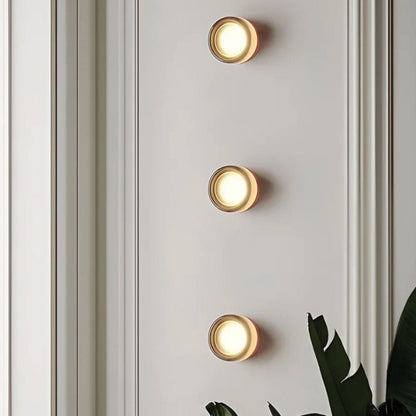 Drie stijlvolle LichtAura wandlampen in modern design, verspreiden een warme gloed op een witte muur met subtiele lambrisering, ideaal voor een eigentijds interieur.