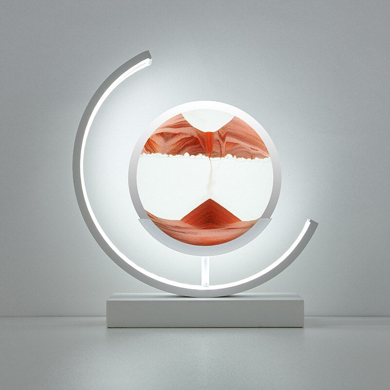 De LumiAura lamp presenteert een adembenemend zandlandschap in warme oranje tinten die langzaam in elkaar vloeien, verlicht door een zacht gloedvormend licht. Dit kunstzinnige ontwerp creëert een rustgevende en magische sfeer, perfect voor een modern interieur. Het bewegende zand in de verlichte cirkel zorgt voor een betoverend effect, ideaal om je ruimte een unieke en kalmerende uitstraling te geven.
