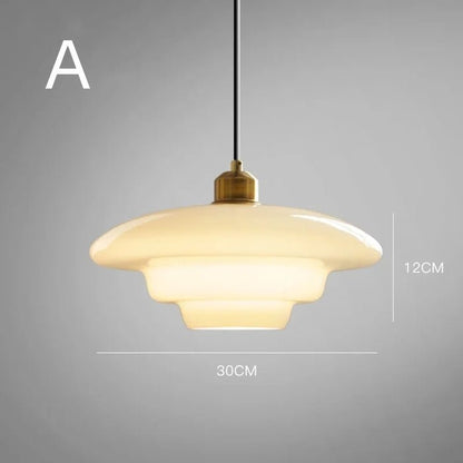  A single elegant white glass pendant lamp with a smooth layered design, suspended from a black cord. The lamp features a brass fixture at the top, adding a touch of sophistication. It measures 30cm in diameter and 12cm in height, perfect for creating a stylish and modern atmosphere in any room. The soft glow of the lamp complements the minimalistic aesthetic.