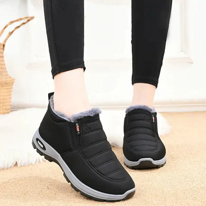Zwarte Tessura schoenen met een zachte, warme voering rond de enkels, ontworpen voor comfort en warmte in de koude maanden. De schoenen hebben een sportieve uitstraling met een grijze zool en zijn ideaal voor dagelijks gebruik.