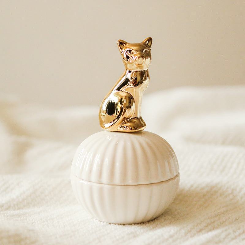 Een elegante opbergpot in de vorm van een schelp, met een gouden kat als deksel. Het verfijnde ontwerp van de kat en de pot maakt het een charmante en stijlvolle manier om kleine voorwerpen op te bergen.