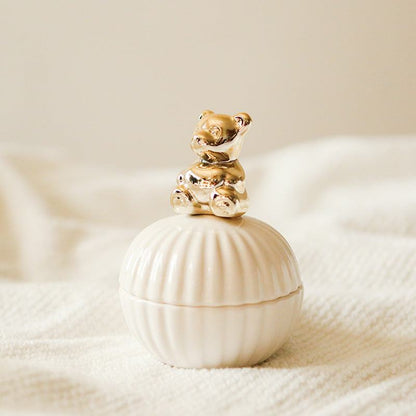 Een elegante opbergpot in de vorm van een schelp, met een schattige gouden beer als deksel. Het verfijnde ontwerp van de beer voegt een speelse en charmante uitstraling toe aan de pot, perfect voor het opbergen van kleine spullen met een vleugje elegantie.